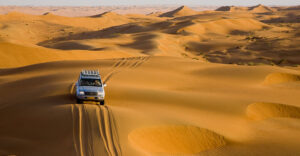 Oman-safari-nurkowanie, obraz przedstawia pojazd typu jeep jadący przez pustynię.